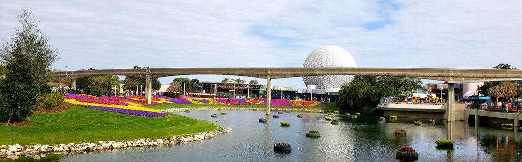 landscape picture of epcot ball and the monorail tracks in front with flowers