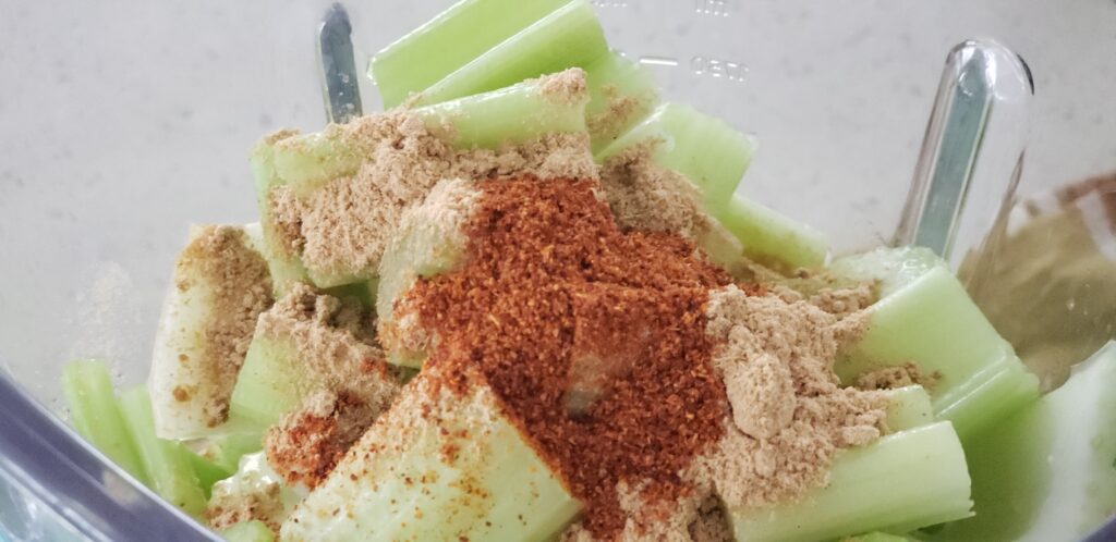blender top with chopped celery - cayenne pepper and powdered ginger