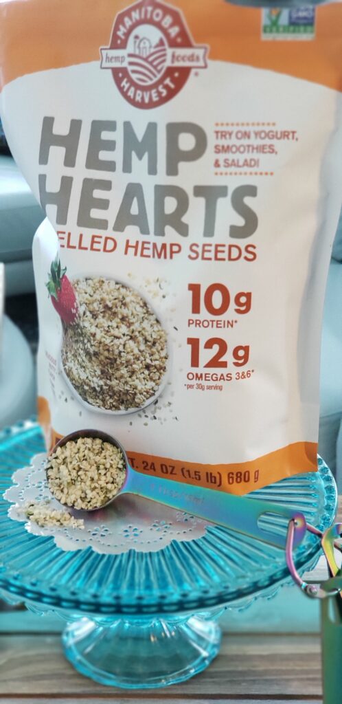 teal stand with  scoop of hemp heart seeds in front of a bag of hemp heart seeds