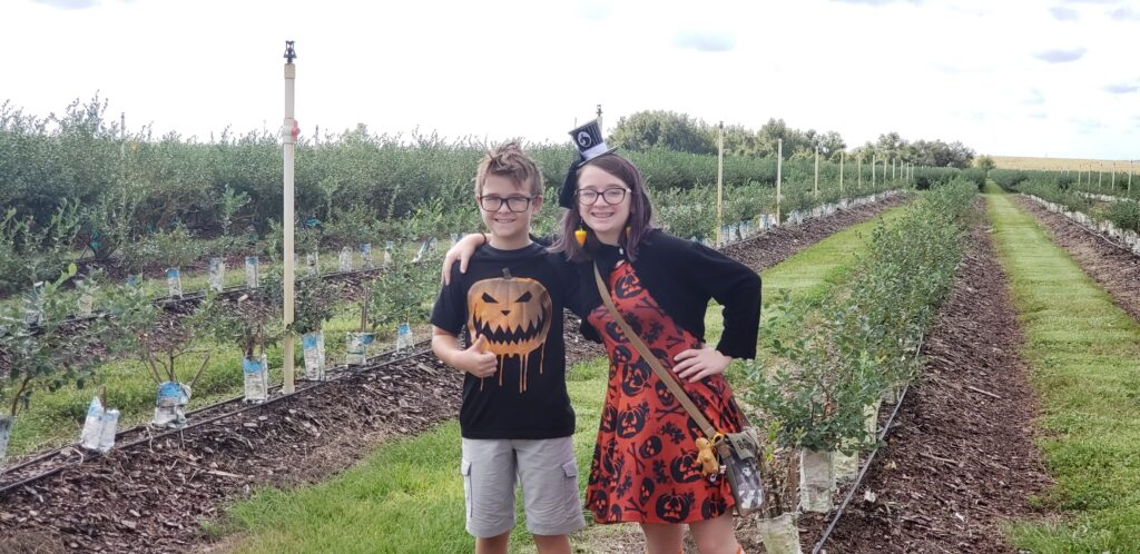 girl and boy in a field with halloween shirts on