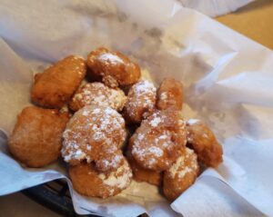 corn fritters with powdered sugar in wax paper