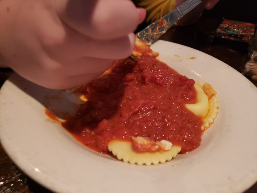 ravioli on a plate with girls hands in way