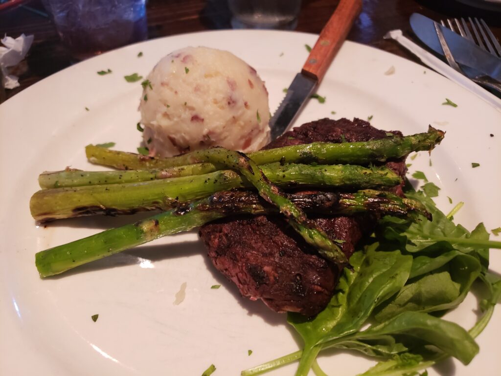 burnt steak on plate with mashed potato with asparagus