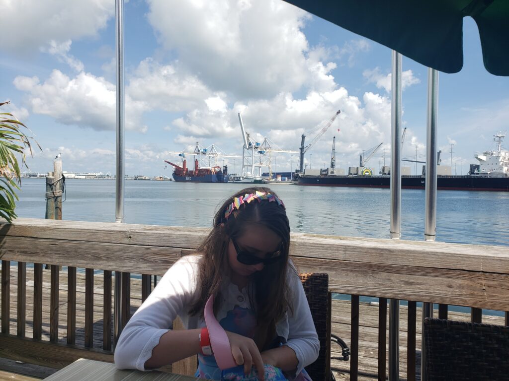 a girl at a table with the port behind her