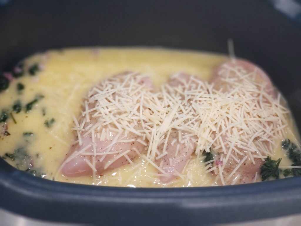 crockpot with chicken adn cheese sprinkled on top