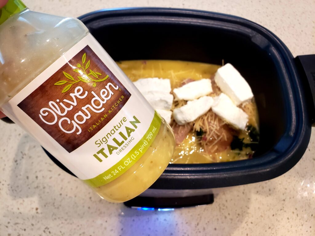 crockpot with chicken and cream cheese in it and olive garden dressing over it