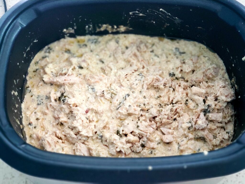 creamy chicken in crockpot with cheese on top