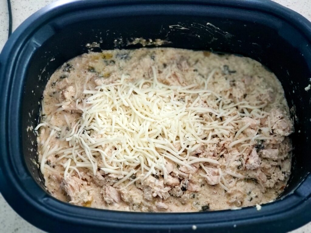 creamy chicken in crockpot with cheese on top