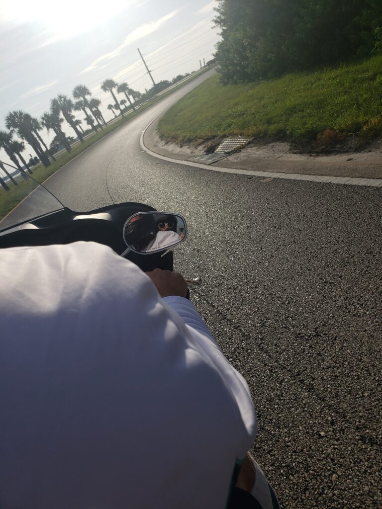 mans shoulder on a motorcycle and the road infron of hime