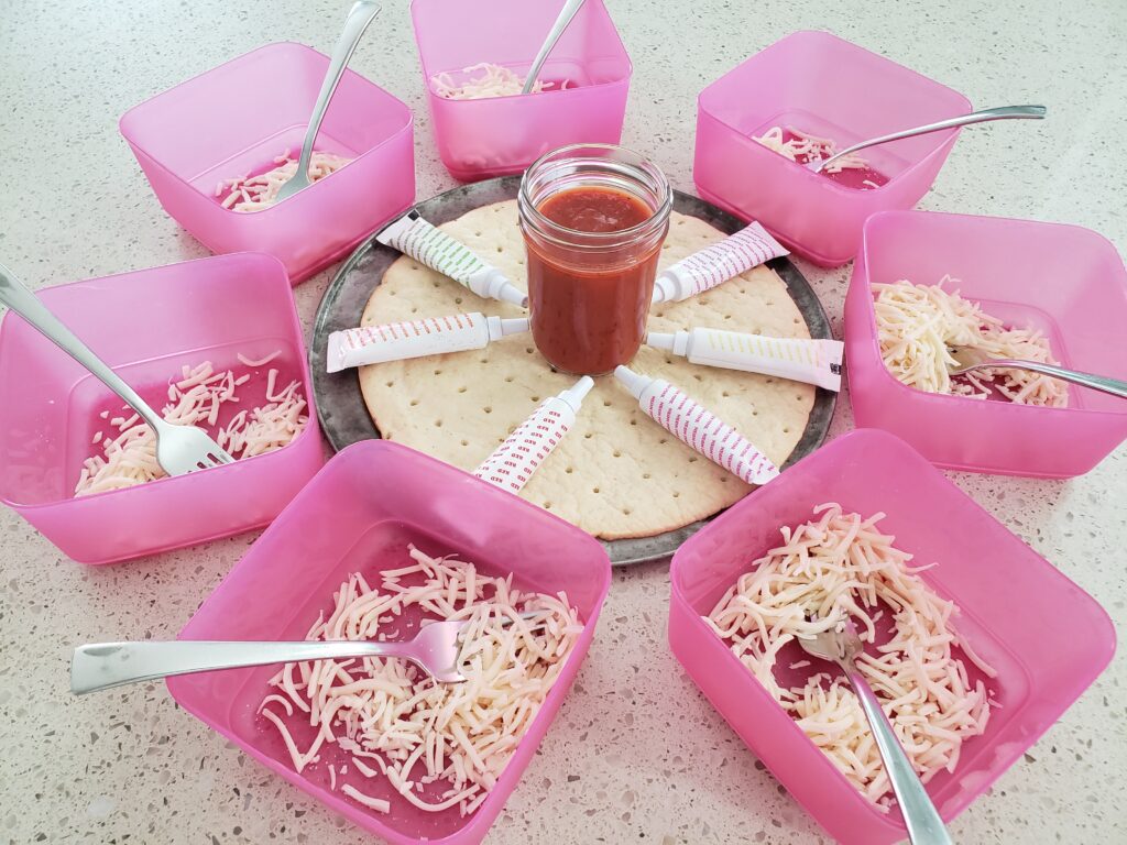 7 pink bowls flled with cheese - with crust in the middle and red sauce