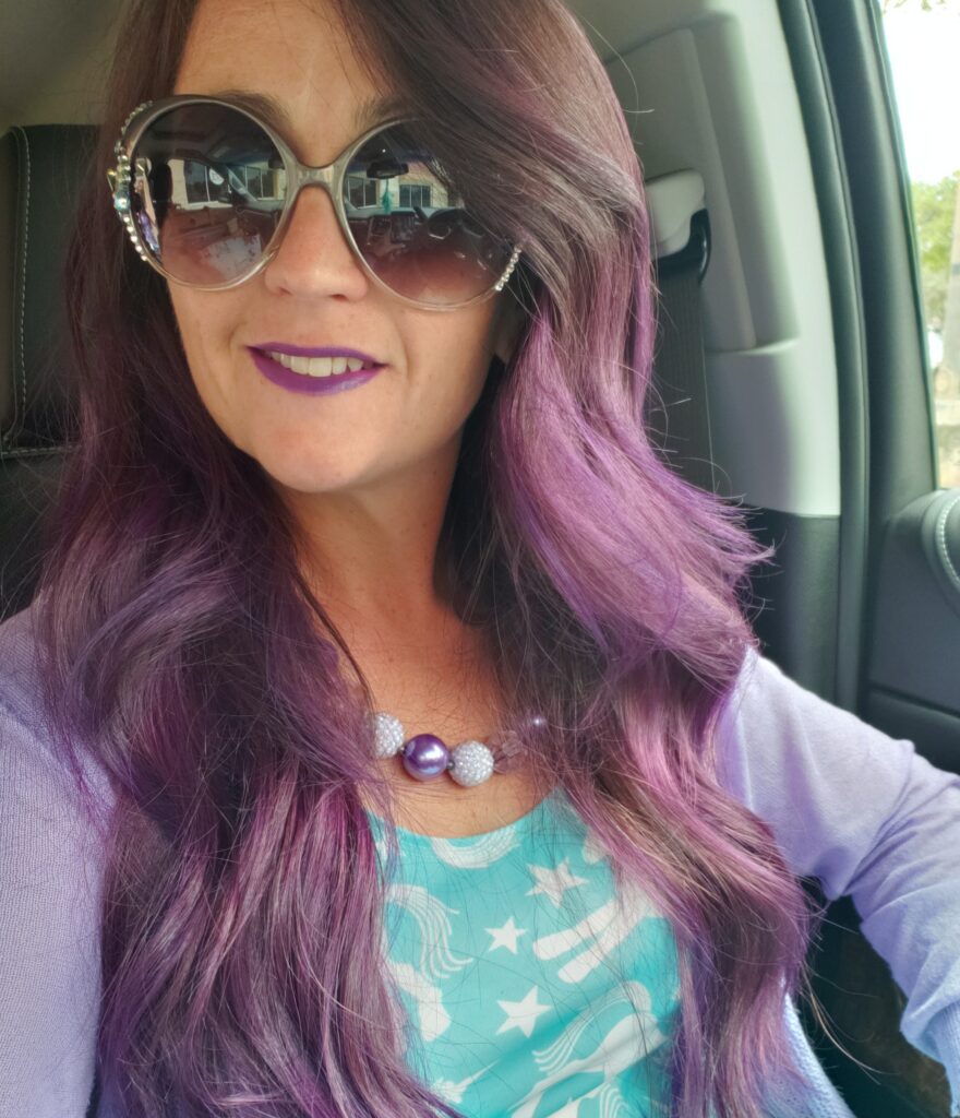 a girl with purple hair and sunglasses smiling