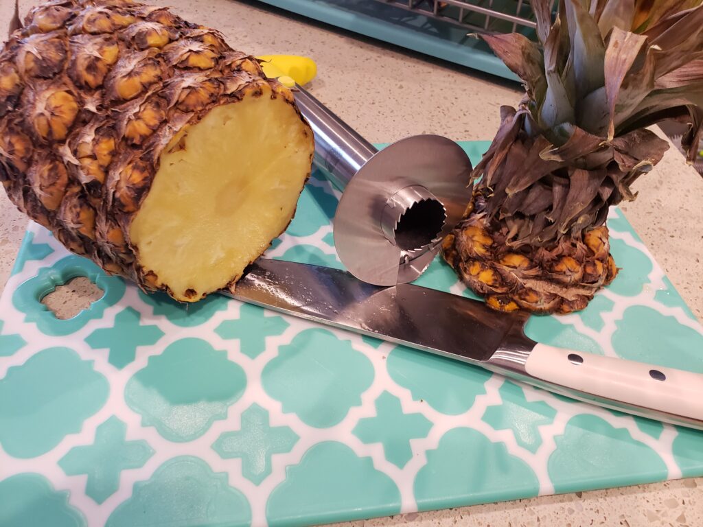 pineapple on a cutting board with the pinepple corer and knife
