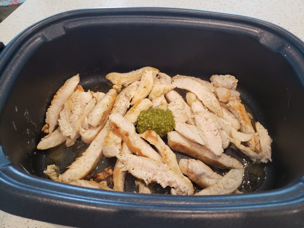 chicken with pesto sauce on it in a pan