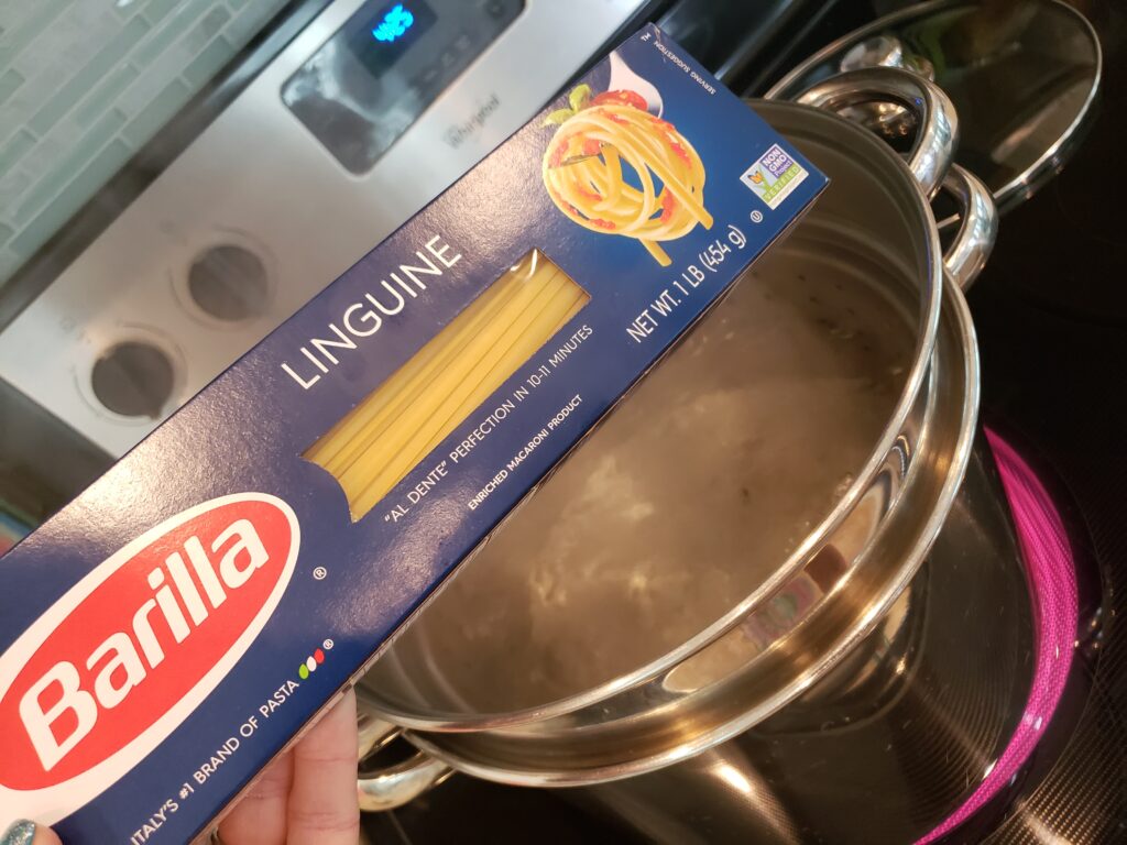 pot with water boiling and a box of pasta above it