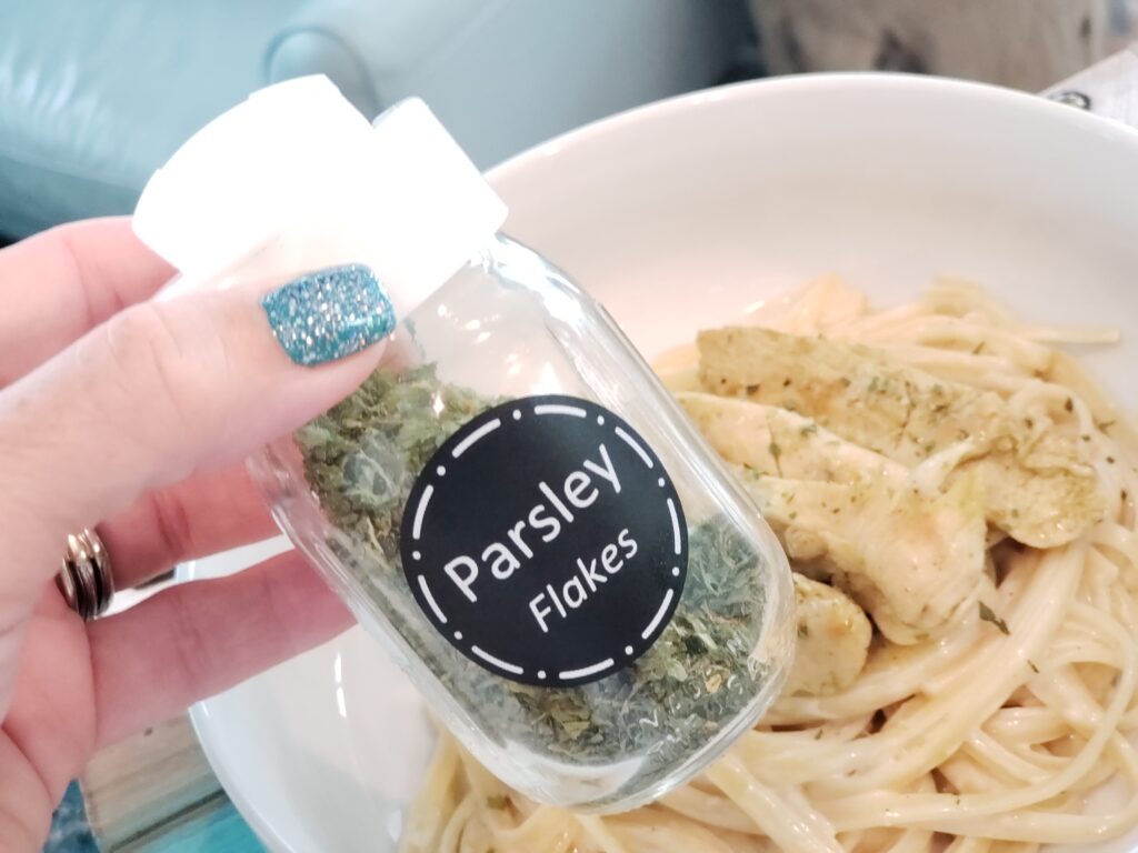 parsley in a jar above a bowl of pasta