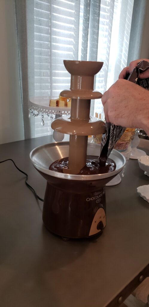 The Epic Chocolate Fountain on a table with man putting chocolate into the fountain