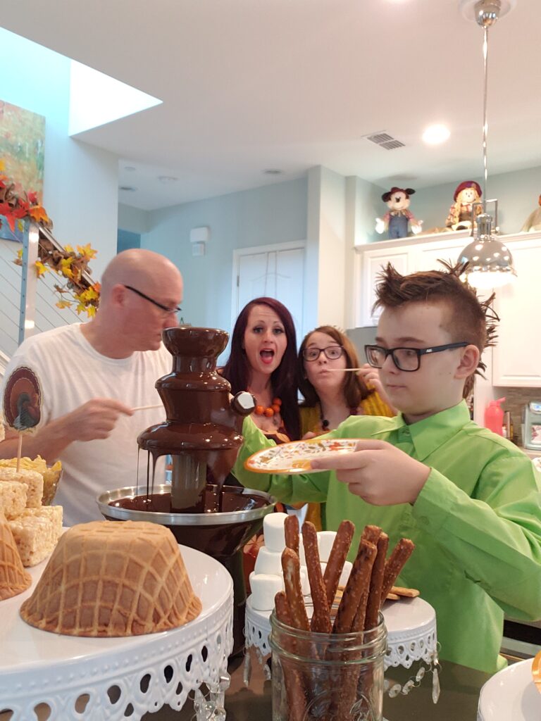 family smiling loading their plates with food from the epic chocolate fountain