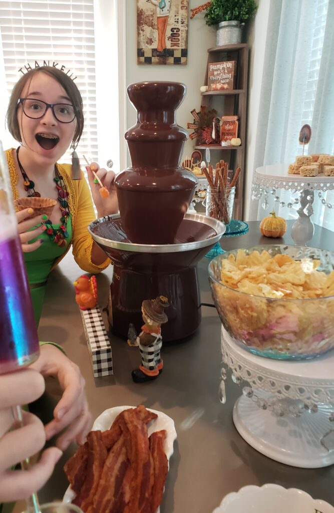 a girl smiling at the chocolate fountain