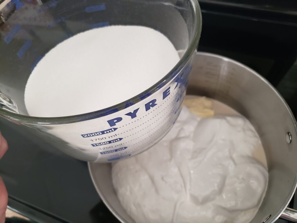 sugar being added to the fluff for fudge