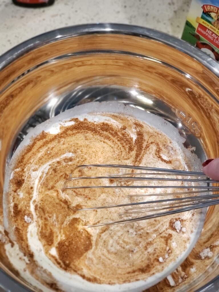 cream and spices being whisked into a bowl