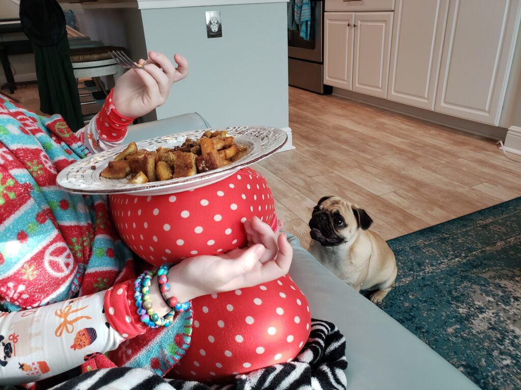 girls eating - french toast on a plate with pug infront of her