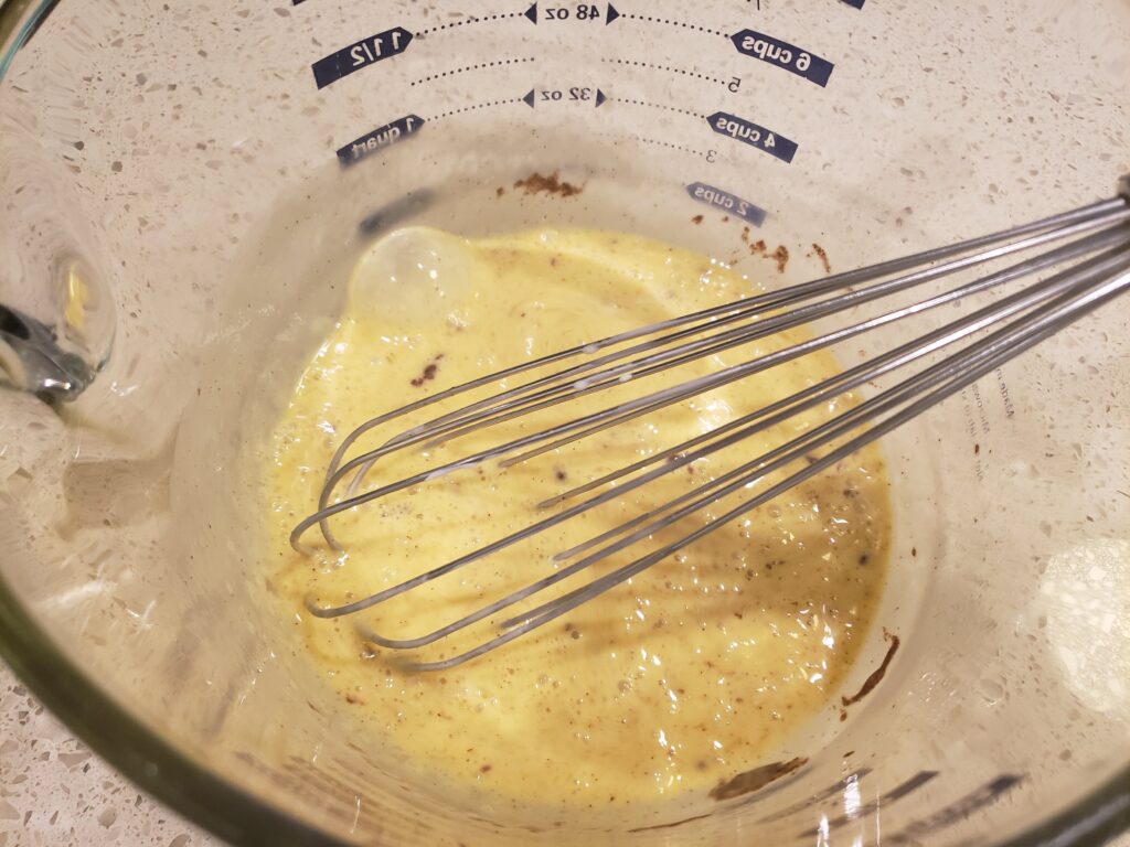 egg batter in a bowl with a wire beater in it