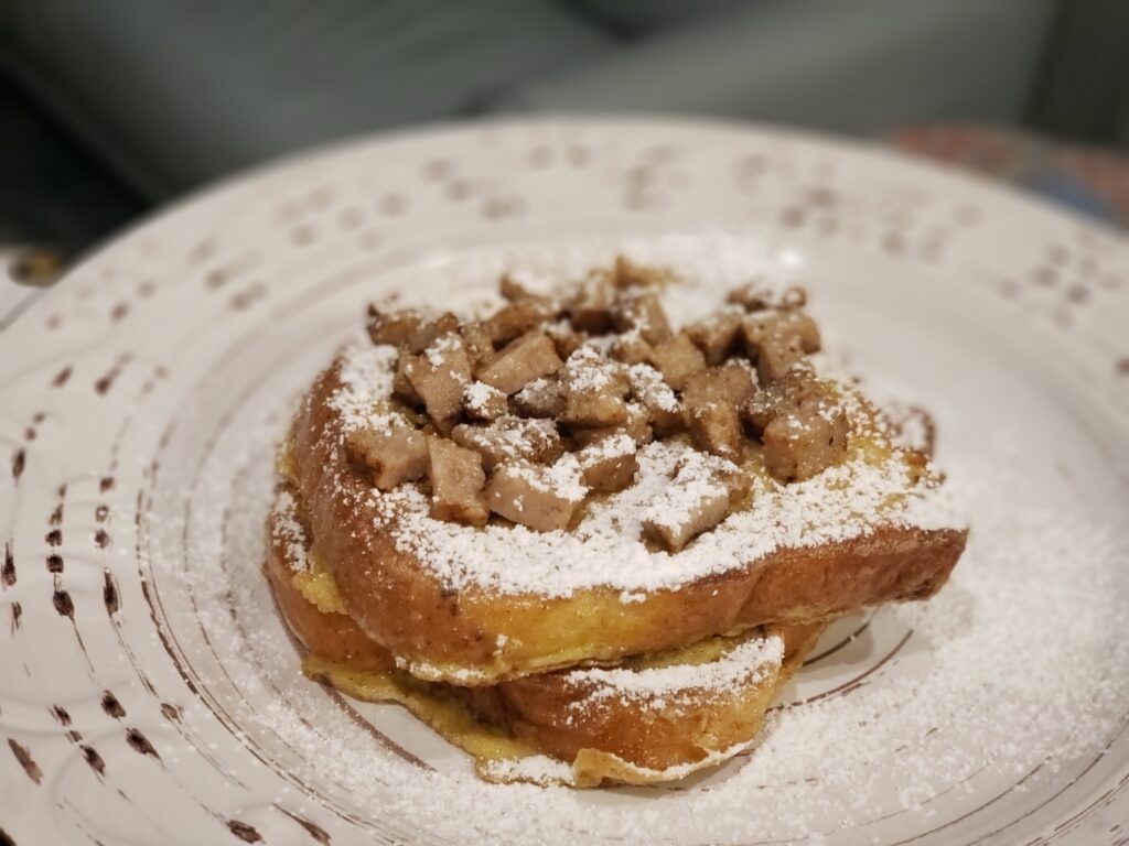 french toast on a plate with a sausage on top