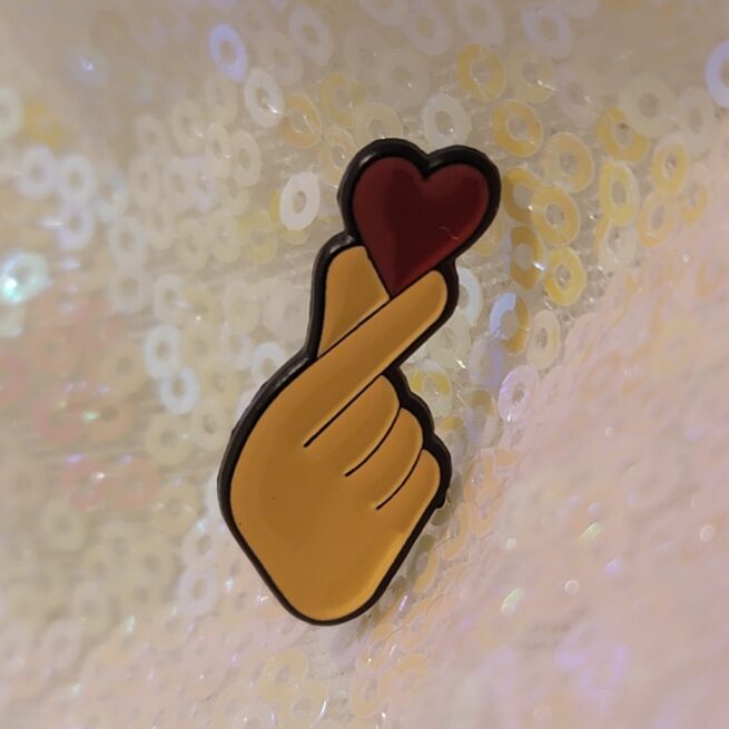 fingers holding a heart pin